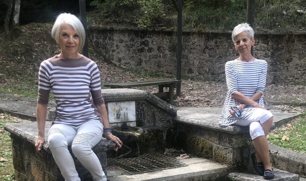 Two women sitting by a fountan