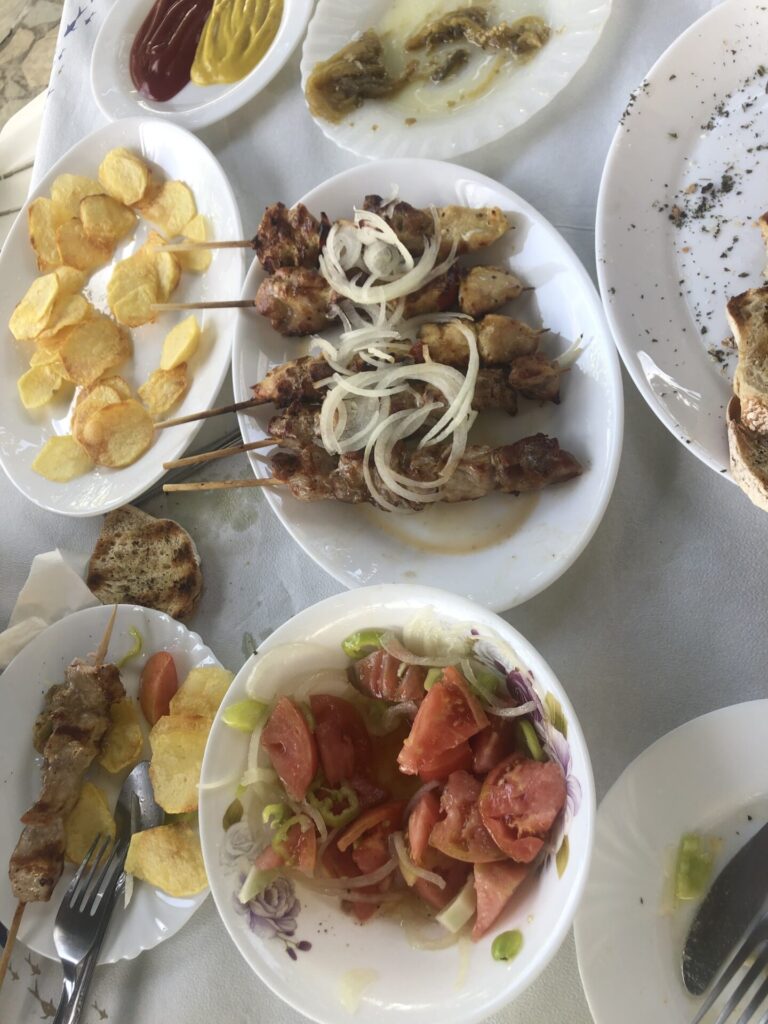 Food on a table, skewers of meet, salad, fried potatoes